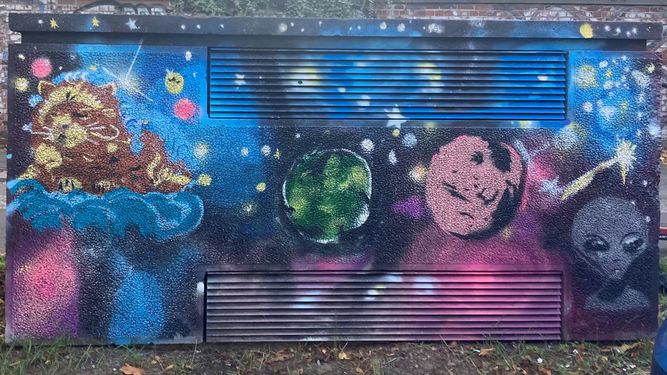 Ein mit einem kosmischen Motiv bemalter Stromkasten zeigt die Erde umgeben von Kometen und Figuren. Sterne, Galaxien und bunte Nebel füllen den Hintergrund.