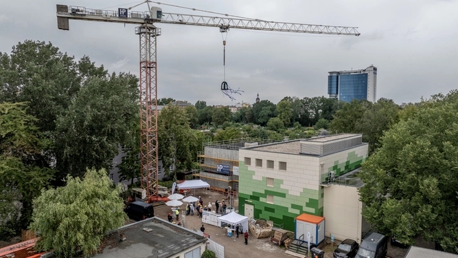 Kran mit Richtkranz vor einem neugebauten Gebäude.