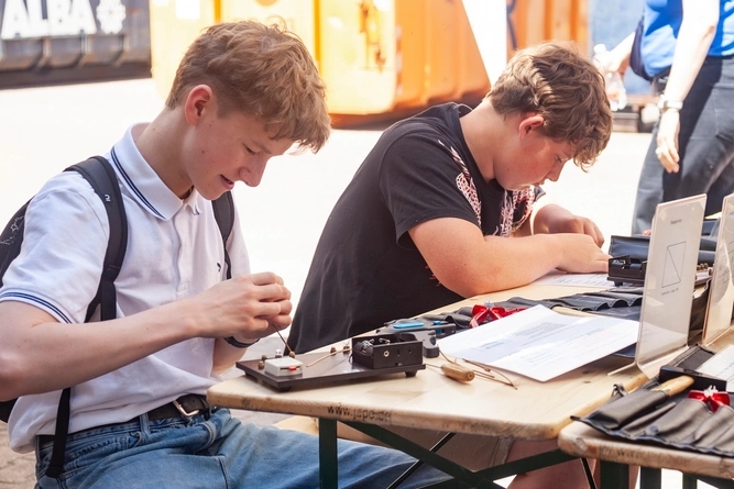 Zwei Jungen Menschen sitzen an einem Tisch und schrauben.