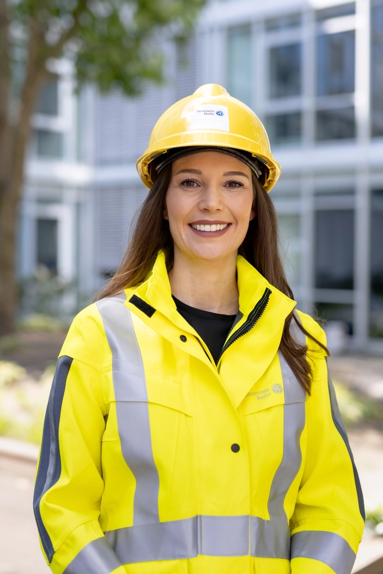 A woman in bright PPE with a helmet.