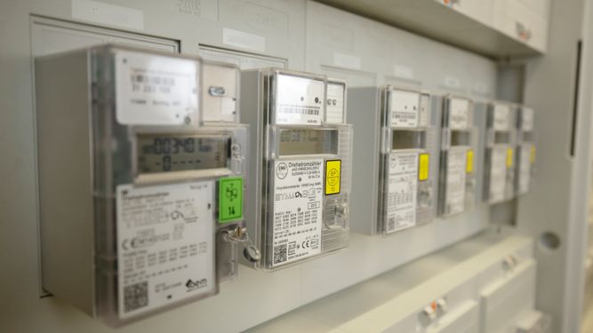Row of modern electric meters mounted on a wall, displaying various readings and labels.