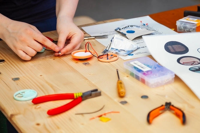 Ein junger Mensch bastelt an einem Holztisch.