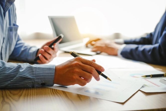 Two unrecognisable people at a desk with documents.