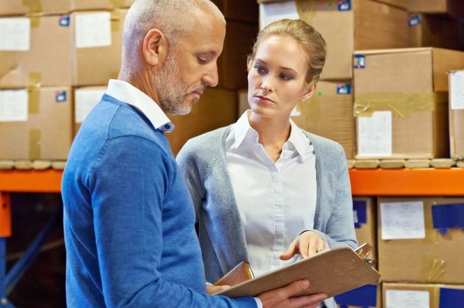 A woman and a man in a meeting in front of a high-bay warehouse.